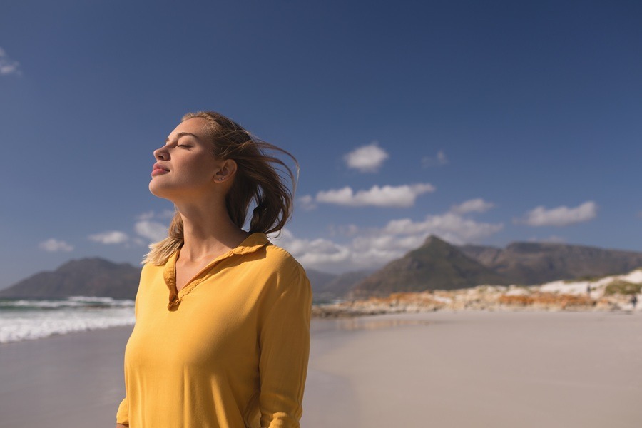 Young woman standing with eyes closed on the beach on a sunny day
